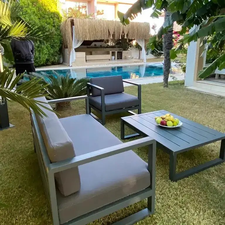 Villa bahçesinin içerisinde krem ve antrasit renginde alüminyum bahçe mobilya takımı